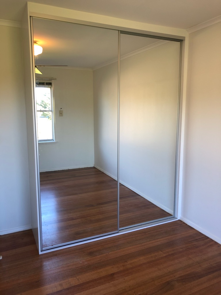 built in wardrobes in white melamine with sliding wardrobe doors - mirror with silver frame and tracks in Laverton